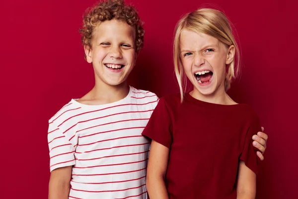 Leuke kleuters emoties staan zij aan zij in alledaagse kleding rode achtergrond — Stockfoto