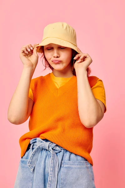 Αστείο κορίτσι σε ένα πορτοκαλί πουλόβερ σε κίτρινο καπέλο μιλώντας στο τηλέφωνο ροζ φόντο αμετάβλητη — Φωτογραφία Αρχείου