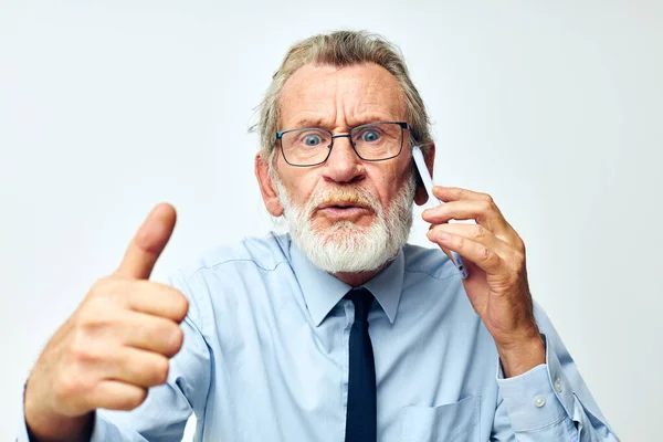 Vieil homme avec téléphone en studio sur fond blanc montre pouce vers le haut — Photo