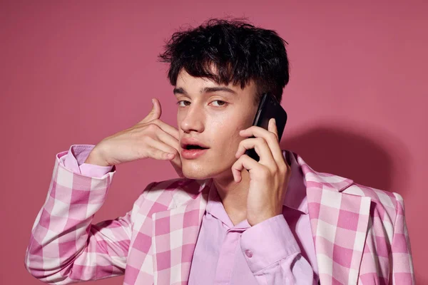 Retrato de un joven con un teléfono en la mano chaqueta rosa moda estilo elegante estilo de vida inalterado — Foto de Stock