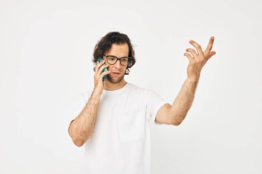 Beyaz tişörtlü çekici bir adam telefon ışığı arka planıyla iletişim kuruyor.