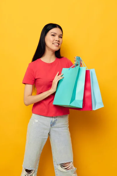 Mooie brunette met kleurrijke tassen poseren winkelen plezier gele achtergrond ongewijzigd — Stockfoto