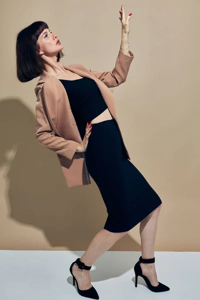 Retrato de uma mulher em uma jaqueta bege estilo elegante posando fundo claro — Fotografia de Stock