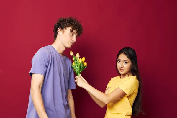 Mladý chlapec a dívka kytice žlutých květin na základě přátelství červené pozadí beze změny — Stock fotografie