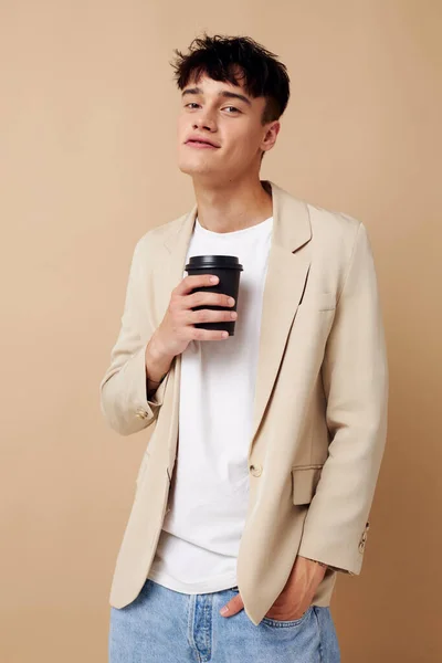 Portrait of a young man black disposable glass in the hands of posing fashion light background unaltered — Stock Photo, Image