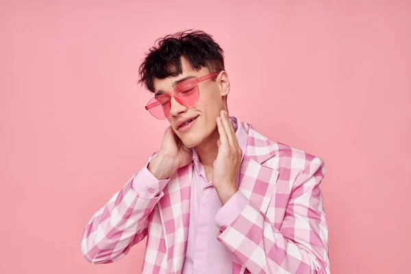 Un joven gafas de color rosa chaqueta a cuadros de moda posando fondo rosa inalterado — Foto de Stock