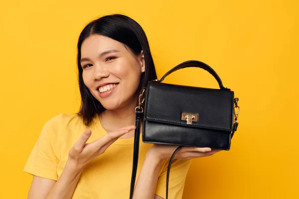 Smiling asian woman woman handbag fashion yellow background — Stockfoto