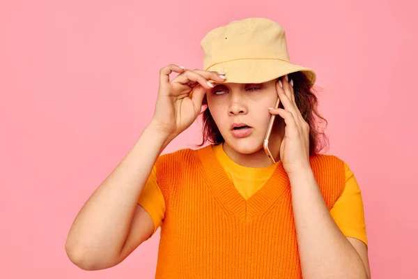 Pretty woman communicates on the phone in yellow hat fashion pink background unaltered — Fotografia de Stock