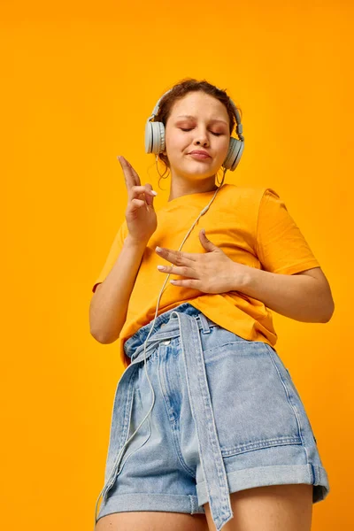 Csinos lány nyári stílus fejhallgató tánc sárga háttér változatlan — Stock Fotó
