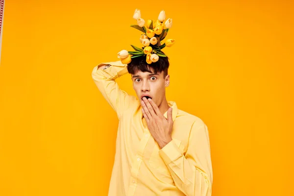 Chico guapo en gafas amarillas con un ramo de flores fondo amarillo inalterado — Foto de Stock