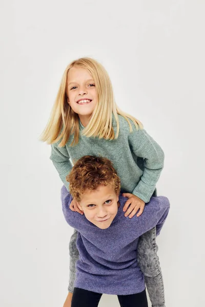 Zdjęcie dwójki dzieci w wielobarwnych swetrach pozujących do zabawy w dzieciństwie bez zmian — Zdjęcie stockowe