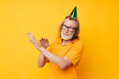 Sarı tişörtlü, kafasında şapkası olan emekli yaşlı bir adamın fotoğrafı.