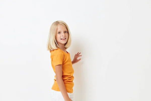 Маленькая девочка с светлыми волосами в желтой футболке на изолированном фоне — стоковое фото