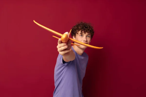 Mladý muž s letadlem hračky v purpurovém tričku červené pozadí beze změny — Stock fotografie