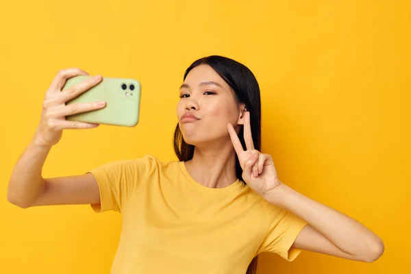 Woman with Asian appearance with a smartphone in hands fun emotions close-up studio model unaltered — Foto Stock