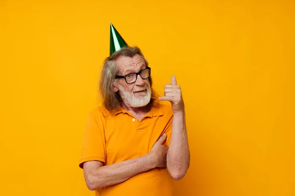 Старший седой мужчина в зеленых очках на голове праздничные эмоции желтый фон — стоковое фото
