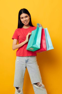 Renkli çantaları olan yakışıklı Asyalı genç bir kadın alışveriş pozu veriyor. Hayat tarzını değiştirmemiş.