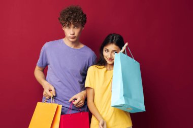 Renkli tişörtlü bir kadın ve erkeğin portresi. Çantalarla alışverişe çıkıyorlar. Değişiklik yok.