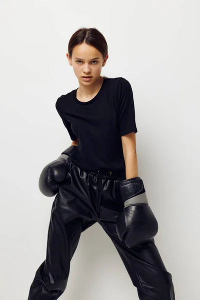 Hermosa chica en negro deportes uniforme guantes de boxeo posando fondo aislado — Foto de Stock