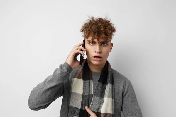 Привлекательный мужчина в клетчатом шарфе разговаривает по телефону, создавая эмоции на изолированном фоне — стоковое фото
