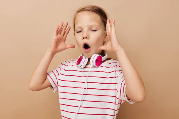 Carino ragazza in strisce t-shirt cuffie gesto mani isolato sfondo — Foto Stock