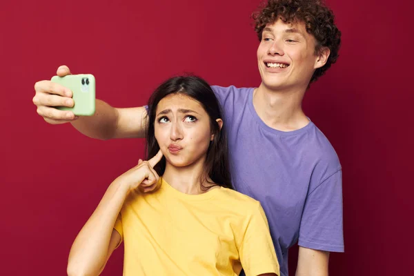Giovane uomo e ragazza stile moderno emozioni divertimento telefono rosso sfondo — Foto Stock