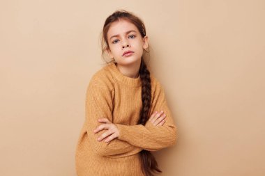 Mutlu gülümseyen kız çocuğunun portresi uzun atkuyruklu bej süveter bej arka plan