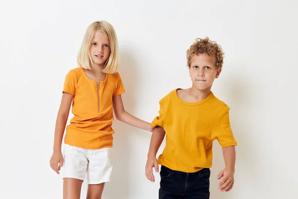 Um menino e uma menina em camisetas amarelas estão ao lado uns dos outros em um fundo leve posando — Fotografia de Stock