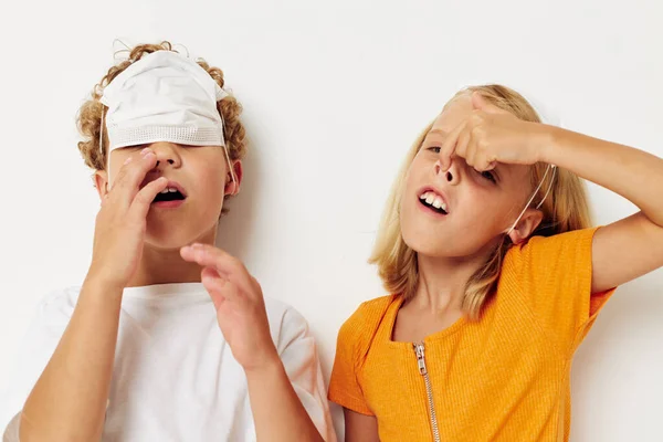 Foto van positieve jongen en meisje leuk medisch masker staan zij aan zij close-up licht achtergrond — Stockfoto