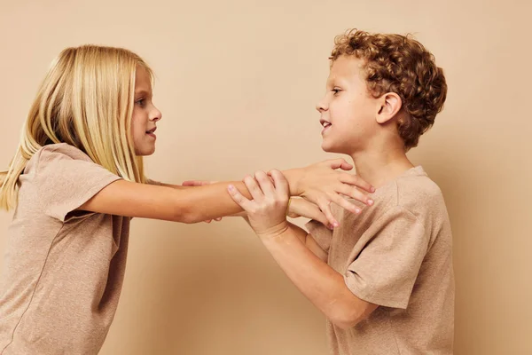 Kleine jongen en meisje in beige t-shirts poseren voor plezier jeugd ongewijzigd — Stockfoto