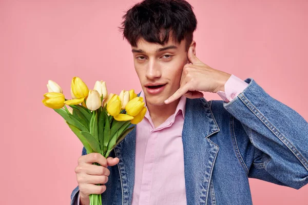 Retrato de un hombre joven ramo de flores amarillas regalo vacaciones elegante estilo rosa fondo inalterado — Foto de Stock