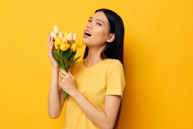 Sarı tişörtlü Asyalı güzel bir kadının portresi. Üzerinde çiçek buketi olan bir tişört. Tatil tatili.