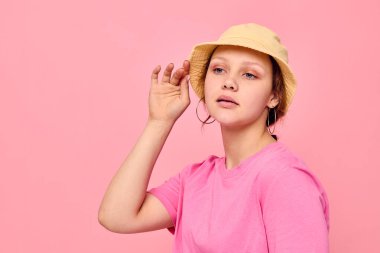 Pembe tişört ve şapka giyen şık bir genç kız mankeni.