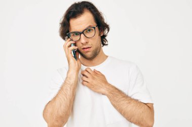 Beyaz tişörtlü neşeli bir adam telefonla iletişim kuruyor.