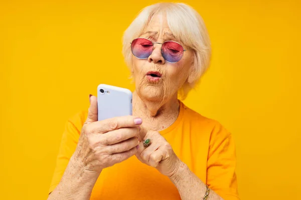 Anciana sonriente hablando por teléfono en tecnologías de gafas amarillas — Foto de Stock