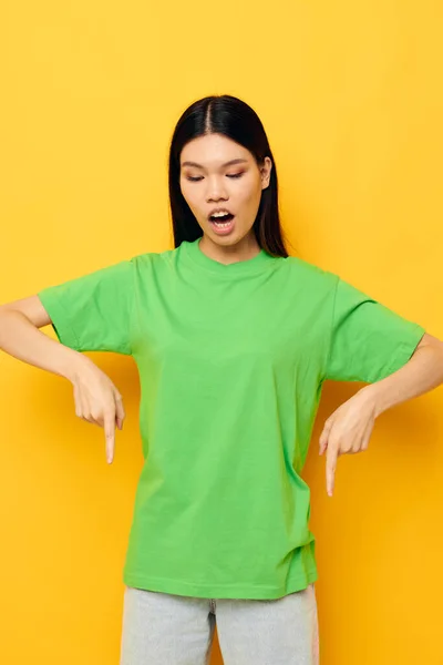Bonita morena posando em verde t-shirt emoções cópia-espaço amarelo fundo inalterado — Fotografia de Stock