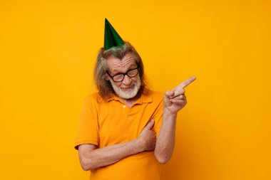 Kafasında şapkası olan sarı tişörtlü yaşlı bir adam portresi.