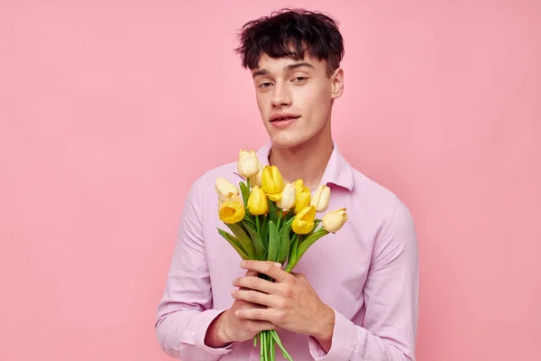Красивий чоловік в рожевій сорочці з букетом квітів жестикулює своїми руками модель студії — стокове фото