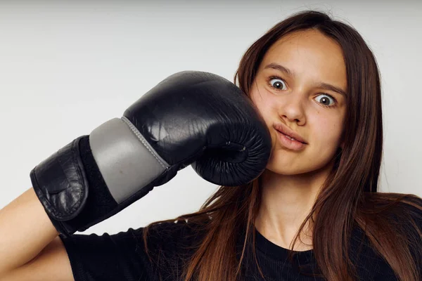 Jonge vrouw in bokshandschoenen punch in zwarte broek en een T-shirt geïsoleerde achtergrond — Stockfoto