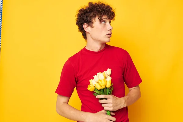 Joven hombre de pelo rizado en una camiseta roja un ramo de flores regalo de vacaciones Estilo de vida inalterado — Foto de Stock