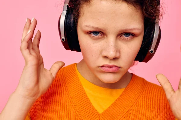 Portrait d'une jeune femme dans un pull orange écouteurs musique divertissement vue recadrée inchangée — Photo