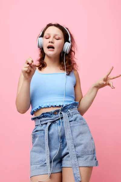 Модная девушка с наушниками музыка весело розовый фон без изменений — стоковое фото