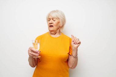 Neşeli yaşlı kadın, günlük tişört gözlükleriyle bir bardak suyla kaplanmış manzaralı.