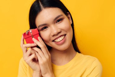 Çekici genç Asyalı kadın elinde hediye kutusuyla monokrom pozu veriyor.