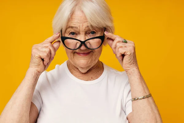 Gülümseyen yaşlı kadın görme sorunları sarı arka planda gözlük — Stok fotoğraf