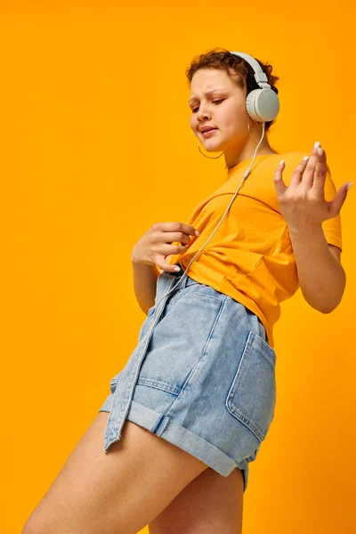 Bonita chica usando auriculares vaqueros pantalones cortos emociones de cerca Estilo de vida inalterado — Foto de Stock