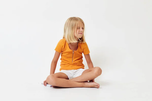 Mała dziewczynka z blond włosami gestykulująca rękami siedząc na podłodze — Zdjęcie stockowe