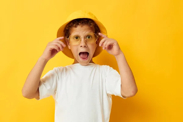 Мальчик в белой футболке в жёлтой шляпе вызывает эмоции — стоковое фото