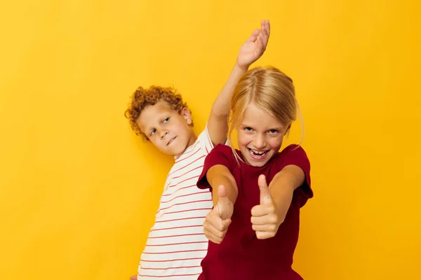 Duas crianças alegres abraçando moda entretenimento infantil fundo amarelo — Fotografia de Stock