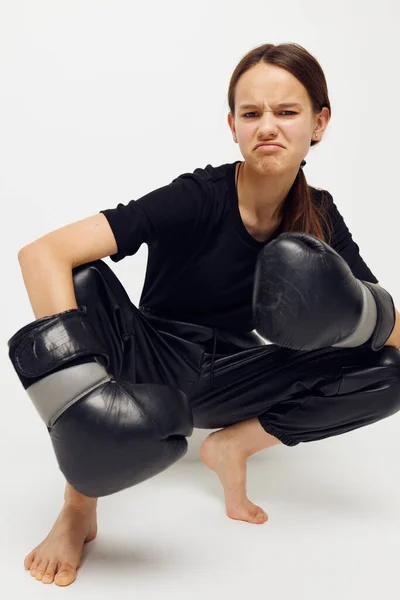 年轻漂亮的女人穿着黑色裤子戴在地板上的拳击手套隔离的背景 — 图库照片